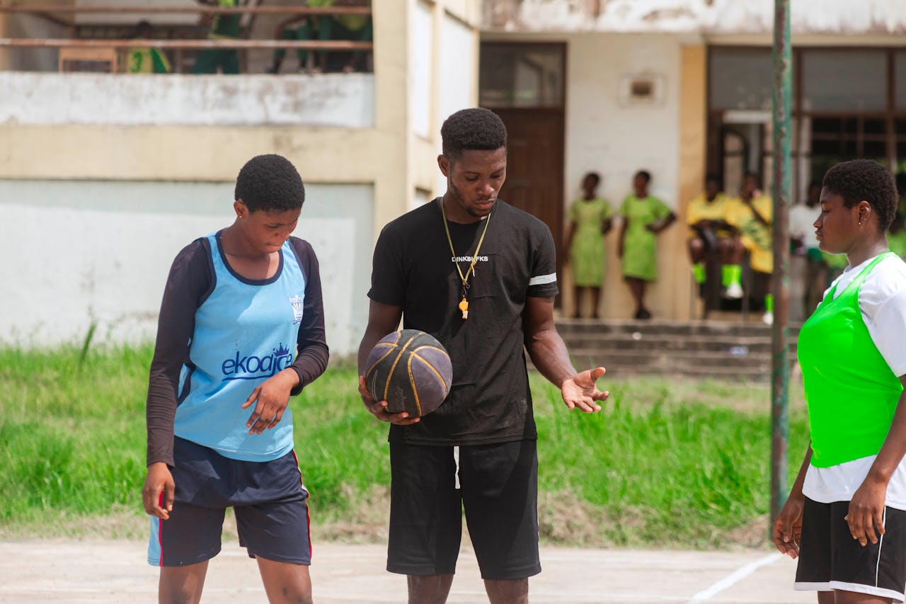 A coach discusses play strategies with his team on an outdoor court.